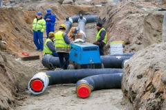 Team of workers in a trench installing district heating pipe